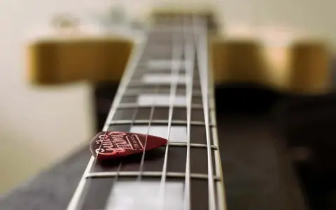 Médiator sur le manche d'une guitare, prêt à jouer une gamme arabe.