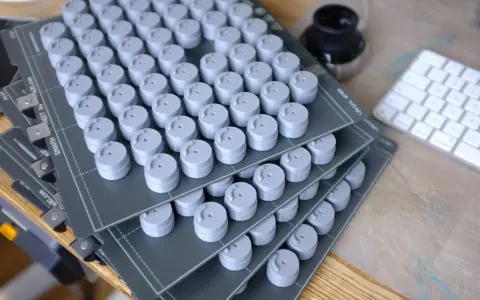 Stosy szarych, cylindrycznych elementów, świeżo po prototypowaniu 3d. Obok klawiatura i kałamarz.