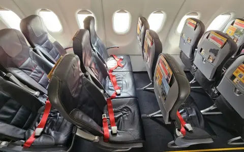 Puste fotele w samolocie Pegasus Airlines, gotowe na odprawę pasażerów. Czerwone pasy bezpieczeństwa czekają.