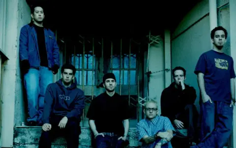 Sześciu członków zespołu Linkin Park, w tym Chester Bennington, pozuje na schodach.