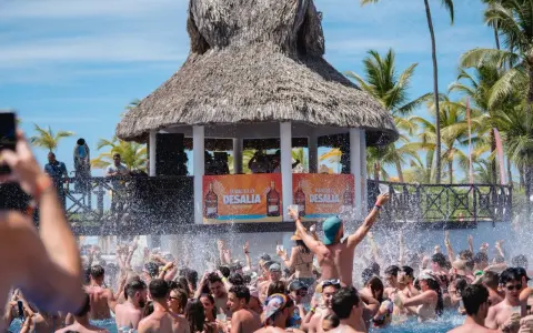 Gente disfrutando en una piscina con un escenario de Barceló Desalia al fondo.