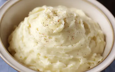 Un cremoso puré de patatas, espolvoreado con pimienta negra y roja, servido en un cuenco.