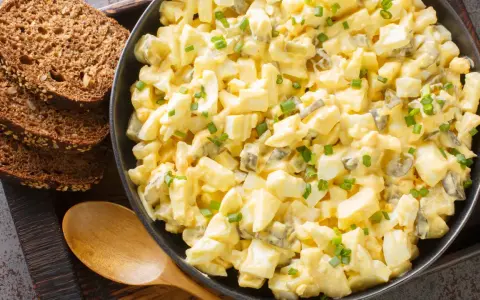 Cremiger Eiersalat mit Gurkenstückchen und Schnittlauch, garniert, serviert mit Vollkornbrot. Ein einfaches eiersalat rezept.