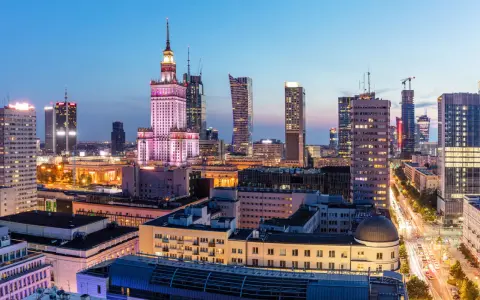 Warszawski krajobraz miejski nocą, z Pałacem Kultury i Nauki w centrum. Wiele nowoczesnych budynków, gdzie znajdują się uczelnie prywatne Warszawa.