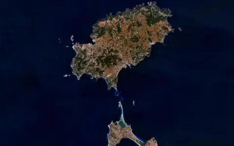 Widok z kosmosu na wyspy Ibiza i Formentera, gdzie jest Ibiza. Widać zielone wzgórza i zabudowania.