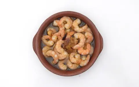 Gambas al pil pil burbujeantes en cazuela de barro, con ajo y aceite de oliva.