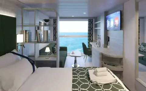Interno cabina MSC World Europa: letto, divano, scrivania e vista mare.