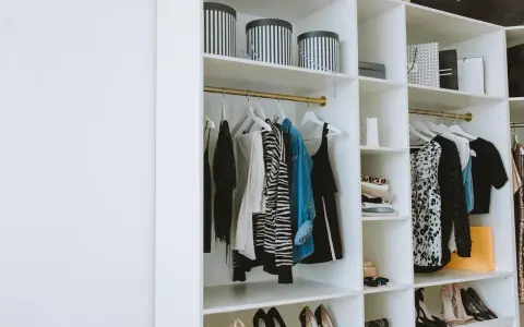 Un armario organizado con ropa colgada y doblada, cajas a rayas y bolsas de compras. Una guía visual de como organizar un armario de forma elegante.