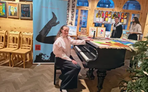 Młoda artystka przy pianinie, gotowa do wykonania piosenki "zimna woda". W tle baner z jej imieniem i nazwiskiem.