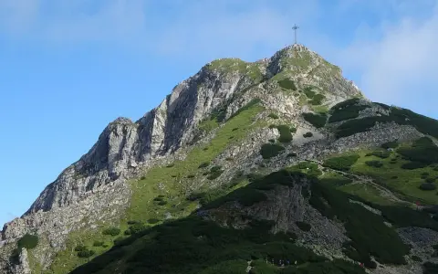 Szczyt Giewontu z krzyżem, zielone zbocza, kamienie i ścieżka. Wjazd na Giewont jest darmowy, ale wymaga wysiłku.