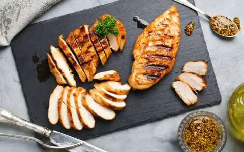Deliziosa tagliata di pollo grigliata, servita su ardesia con senape e prezzemolo.