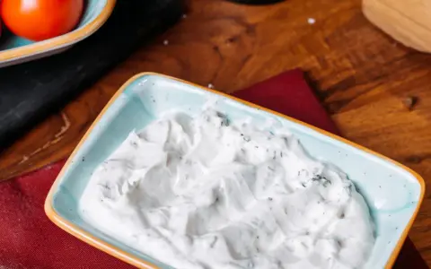 Sauce roquefort crémeuse et onctueuse, parsemée d'herbes vertes, dans un plat bleu clair. Parfait pour accompagner vos plats.