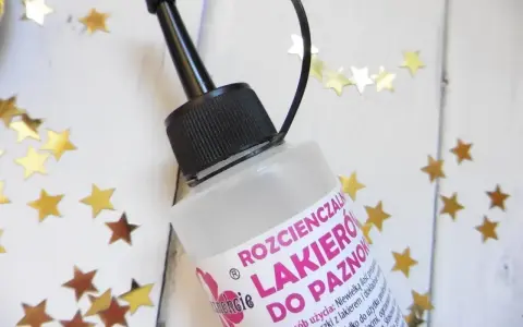 Butelka rozcieńczalnika do lakieru do paznokci, otoczona złotymi gwiazdkami.