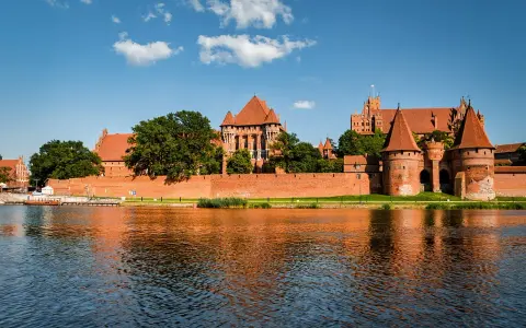Potężny zamek w Malborku odbija się w wodzie. Zastanawiasz się, ile trwa zwiedzanie zamku w Malborku?