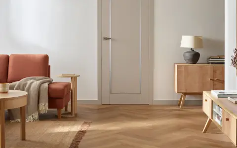 Nowoczesne wykończenie drzwi wewnętrznych w stonowanym kolorze, idealnie komponuje się z drewnianą podłogą i meblami.
