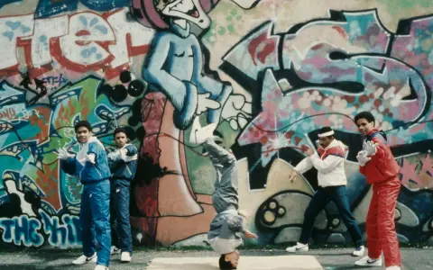 A group of young people showcase their moves in front of vibrant graffiti art, embodying the spirit of hip hop culture art.