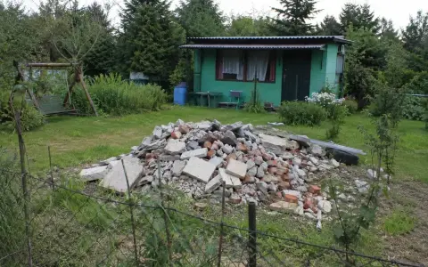 Kupa gruzu na działce ROD. Czy komornik może zająć działkę ROD? W tle zielona altanka, huśtawka i drzewa.