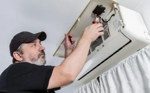 Técnico revisa un aire acondicionado. ¿Cuanto dura un aire acondicionado? El mantenimiento es clave para su longevidad.