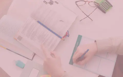 Uczniowie studiują, a na biurku leżą książki, okulary i kalkulator. Czy oceny na studiach mają znaczenie?