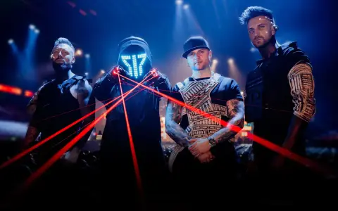 Medlemmar av Smash Into Pieces poserar med röda laserstrålar framför en mörk bakgrund med blå ljus.