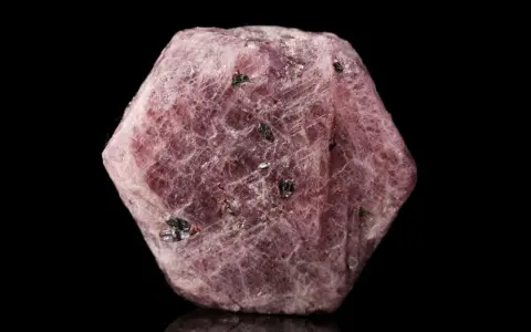Cristallo grezzo di corindone rosa, con inclusioni scure. Il corindone, con il suo significato di forza e passione, si presenta in questa forma naturale.