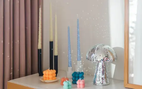 En samling av DIY ljus i olika former och färger, inklusive bubbel- och vridna ljus, samt en glittrig svampformad dekoration.