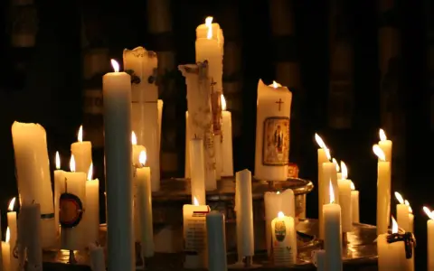Viele Kerzen brennen in der Dunkelheit, einige mit Bildern und Kreuzen verziert. Ein stimmungsvolles Bild, das an Maria Lichtmess erinnert.