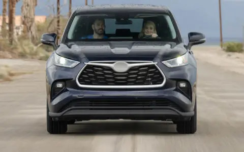 A couple in a dark SUV drive on a dirt road. They might be wondering how long to wait for jump start if the car dies.