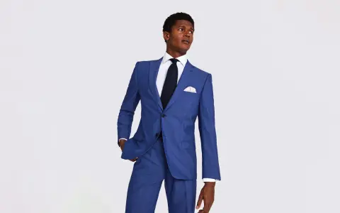 A man in a sharp blue suit, white shirt, and dark tie. This image helps answer how much should a suit cost.
