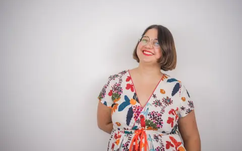 Une femme souriante porte une robe d'été colorée, un modèle inspiré d'un patron gratuit de robe Charlotte.