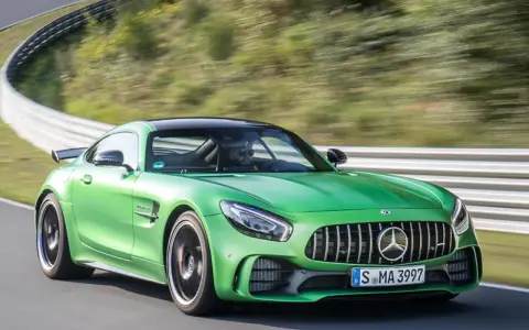 Grüner Mercedes-AMG GT R auf Rennstrecke, Fahrer im Fokus.