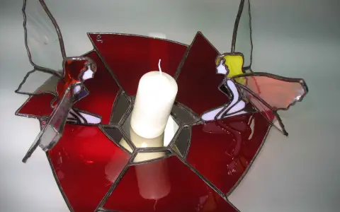 Un photophore vitrail aux couleurs vives, orné de deux anges aux ailes translucides, tenant une bougie blanche.