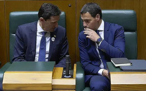 Dos hombres de traje azul conversan en un parlamento. Uno, con corbata de puntos, escucha atentamente. El otro, con la mano en la barbilla, parece reflexionar. ¿Qué debate se estará gestando?