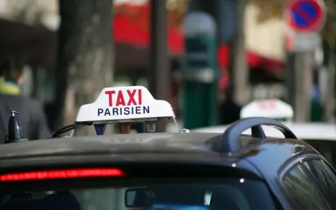 Ein Taxi in Frankreich, mit der Aufschrift "TAXI PARISIEN", wartet auf Fahrgäste.
