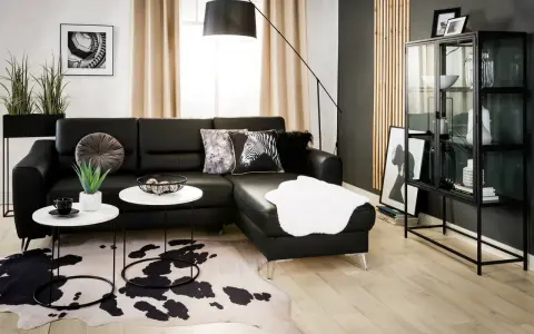 Nowoczesny salon z czarną kanapą i dywanem w cętki. Inspiracje dla odważnych aranżacji.