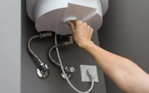Mano girando el dial para cerrar la llave de paso del termo eléctrico.