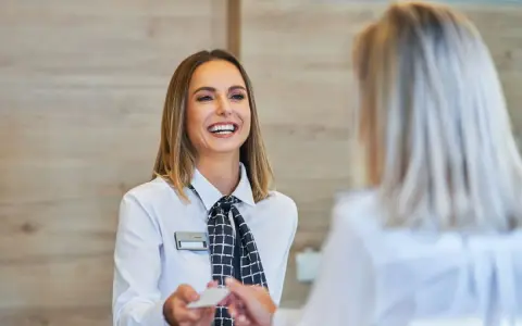 Una sorridente hostess di terra consegna una tessera a un cliente.