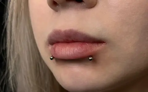 Cyber bites piercing na ustach, podkreślający ich kształt.