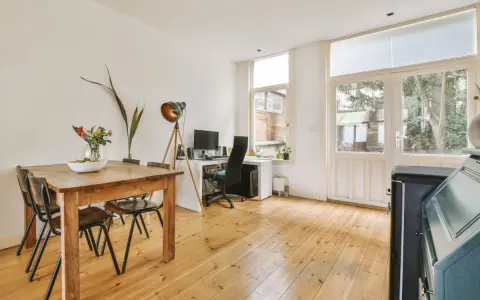 Wygodne biuro w salonie: drewniany stół z krzesłami, biurko z komputerem i lampa.