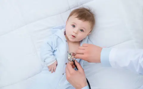 Lekarz osłuchuje dziecko z objawami RSV. Dowiedz się, jak leczyć RSV u niemowląt i dzieci.