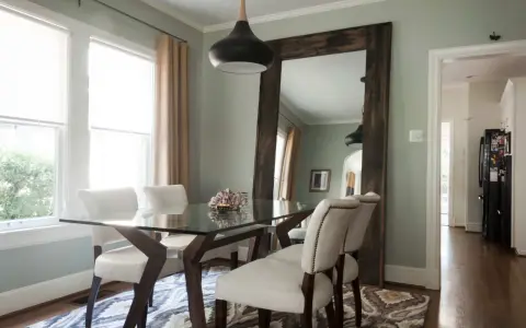 Un grand miroir rustique reflète la salle à manger, offrant une idée de où mettre un miroir dans une salle à manger pour agrandir l'espace.