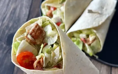 Pyszna tortilla z kurczakiem, chrupiącą sałatą i pomidorkami. Idealna na szybki lunch.