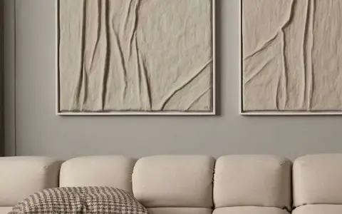 Deux tableaux texturés, style diy tableau relief, aux tons sable, accrochés au-dessus d'un canapé beige.