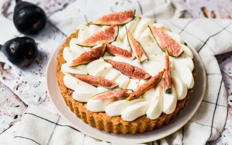 Tarte aux figues fraîches et crème fouettée, décorée de feuilles d'or.