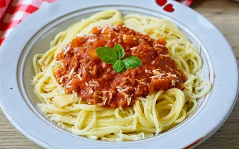 Teller mit Spaghetti Bolognese, bestreut mit Parmesan und garniert mit Basilikum. Perfekt für schnelle Bolognese für Kinder.