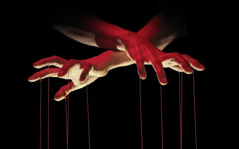 Dłonie jak marionetka, sterujące sznurkami. Czerwone światło podkreśla makiawelizm i manipulację.