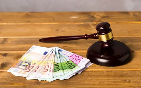 Ein Richterhammer liegt neben Euro-Scheinen. Die Frage "wie lange muss eine Rechtsschutzversicherung bestehen?" wird hier visuell thematisiert.