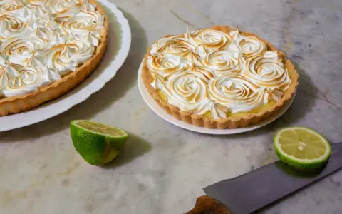 Dos deliciosas tartas de limón con merengue tostado, listas para ser cortadas.