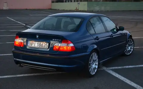 Niebieskie BMW E46 330d na parkingu. Wiele osób chwali ten model za osiągi i komfort.