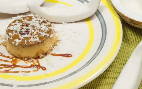 Flan coco on a plate, garnished with coconut flakes and caramel. A perfect dessert for your recette flan coco lait concentré Nestlé.